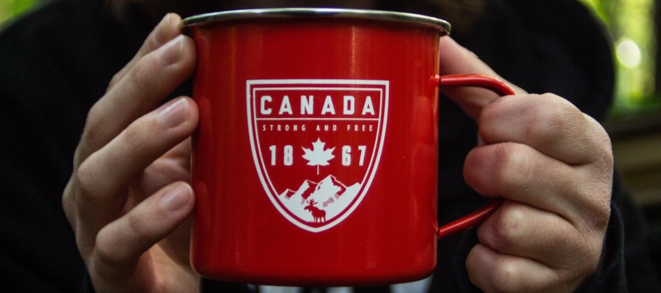 Man holding a red Canada metal cup in the forest