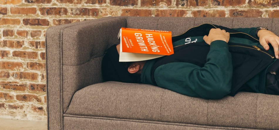 Student with book over his face sleeping on the sofa