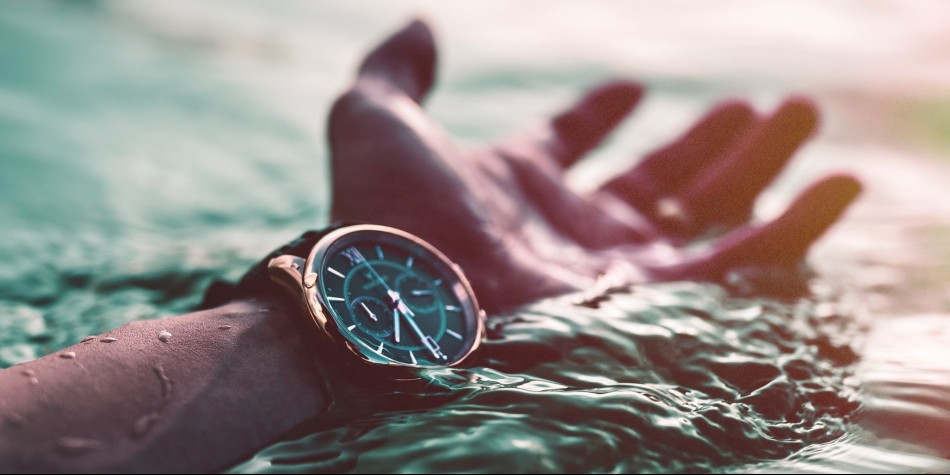 Hand and watch showing time in the water
