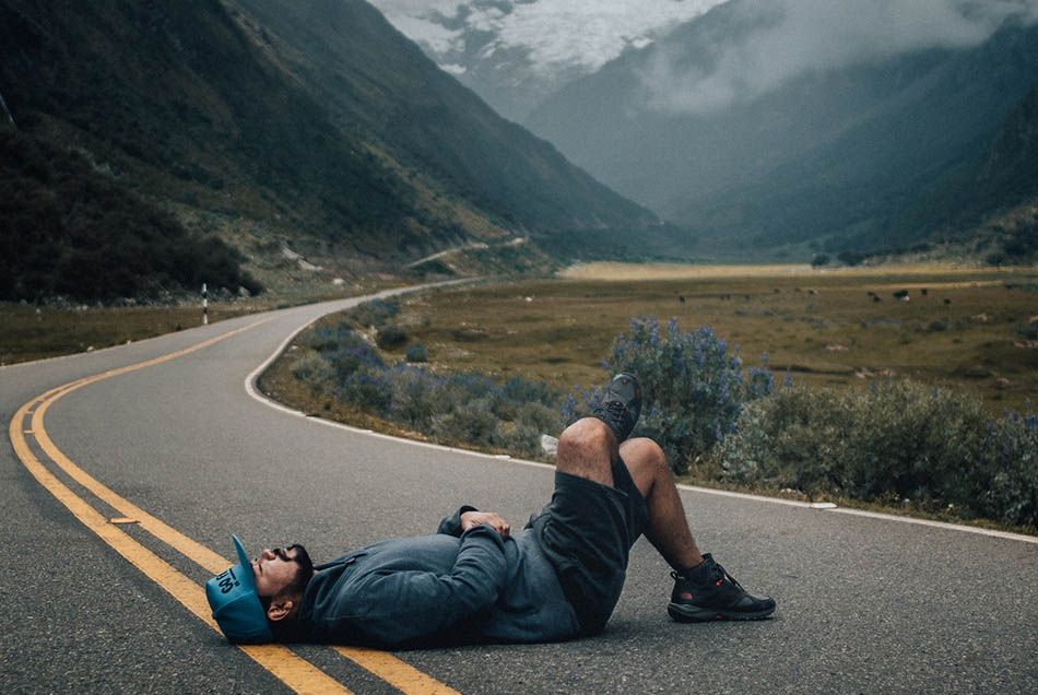 Tired man sleeping on the road in the mountains