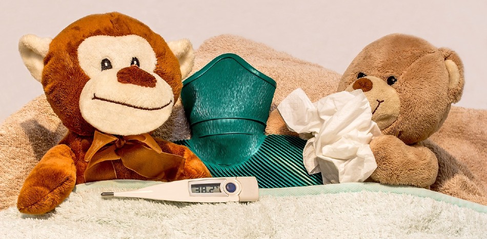 Teddy bears sick in bed with hot water bottle thermometer and tissue
